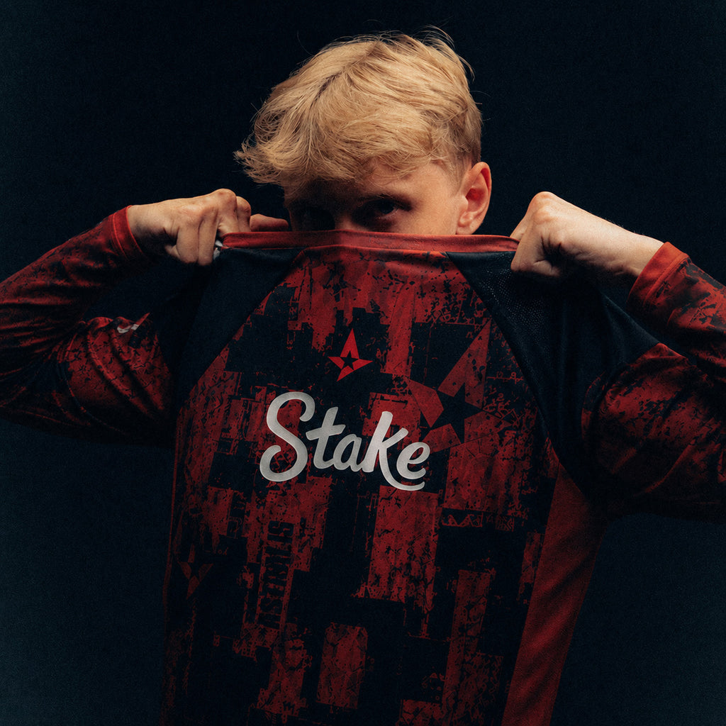 JABBI holding a red and black Astralis jersey with Stake branding against a dark background