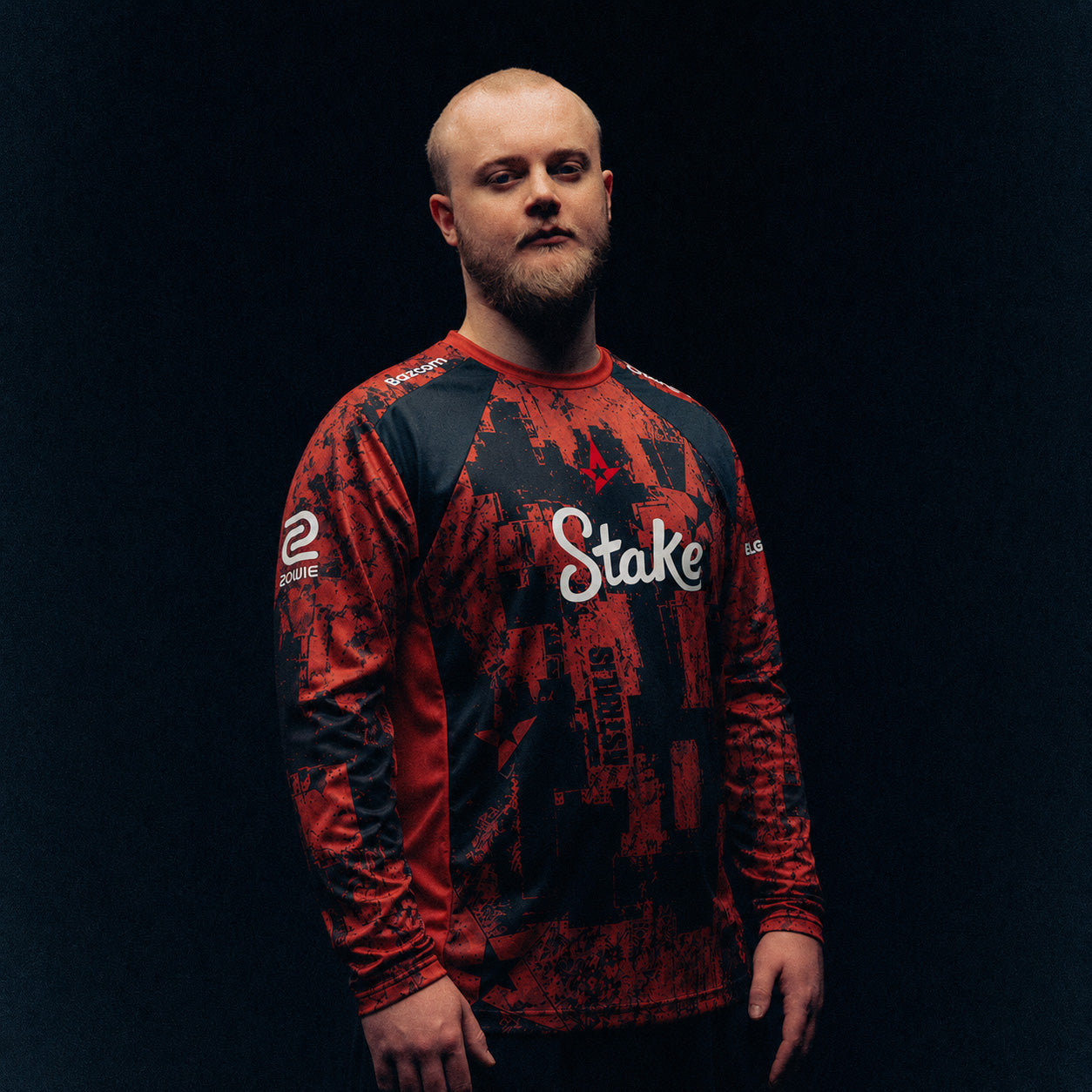 PHZY wearing a red and black patterned Astralis jersey with Stake branding against a dark background