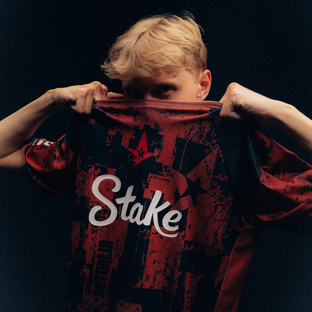 JABBI holding a red and black Astralis jersey with Stake branding against a dark background